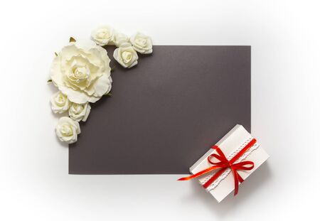 Gift box present decorations flatlay. Gift red ribbon white flowers top view. Congratulation template banner frame white box grey paper copy space backdrop mock up invitation design greeting cardの写真素材