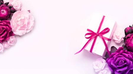 Gift box present decorations flatlay. Gift pink ribbon pink purple flowers top view. Congratulation template long banner white box pink paper copy space backdrop mockup invitation design greeting cardの写真素材