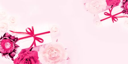 Gift box present decorations flatlay. Gifts pink ribbon pink white flowers top view. Congratulation template long banner white box pink paper copy space backdrop mockup invitation design greeting cardの写真素材