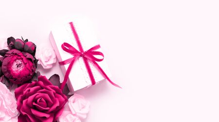 Gift box present decorations flatlay. Gift pink ribbon pink white flowers top view. Congratulation template long banner white box pink paper copy space backdrop mockup invitation design greeting cardの写真素材
