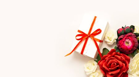 Gift box present decorations flatlay. Gift red ribbon red white flowers top view. Congratulation template long banner white box white paper copy space backdrop mockup invitation design greeting cardの写真素材