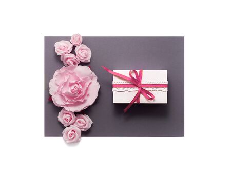 Gift box present decorations flatlay. Gift, ribbon, pink white flowers top view. Congratulation template banner frame white box grey paper copy space backdrop mock up, invitation design greeting cardの写真素材