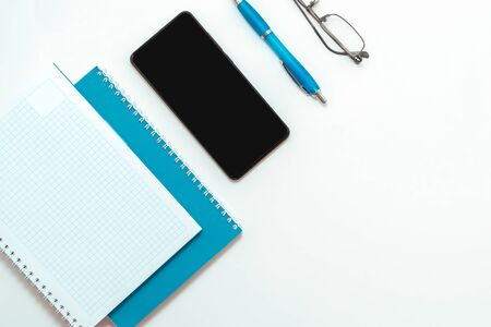 Stay at home white background flatlay. Home office smartphone blue notebook glasses blue pen top view template long banner. Copy space backdrop mock up design. Distance education creative work conceptの写真素材