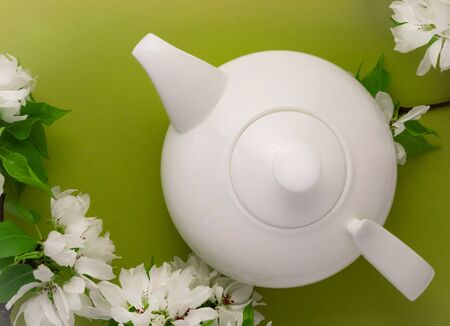 White tea pot and blossom flowers on greenの写真素材