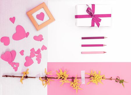 Yellow flowers blossom branch hearts gift box pencils white pink background flat lay. Top view template long banner. Copy space backdrop mockup design. Floral beautiful frame fresh invitation conceptの写真素材