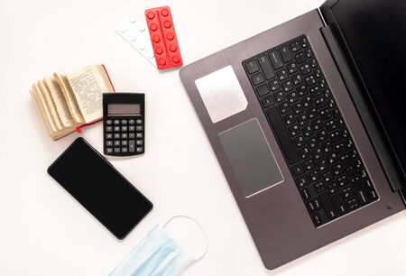 Stay at home white background flatlay. Home office computer laptop smartphone dictionary medical mask tablets pills strips top view template long banner. Copy space mock up. Distance education work.の写真素材
