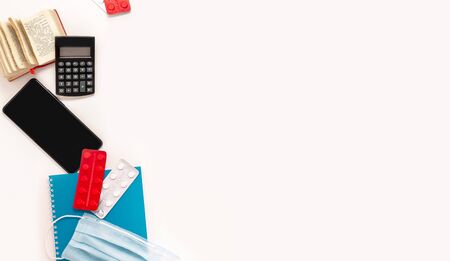 Home office smartphone, dictionary, medical mask, tablets pills strips on whiteの写真素材