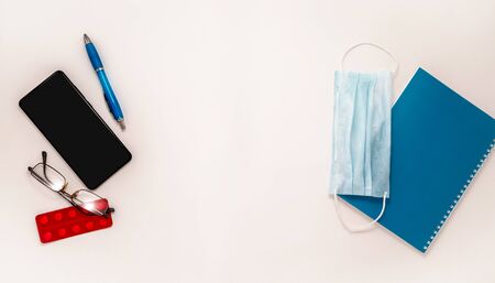 Stay at home white background flatlay. Home office smartphone dictionary medical mask glasses pills strips top view template long banner. Copy space backdrop mock up. Distance education work concept.の写真素材