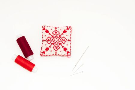 Flat lay with handmade red embroidered needle pad, thread spools, pins, needles, mock up, top view....