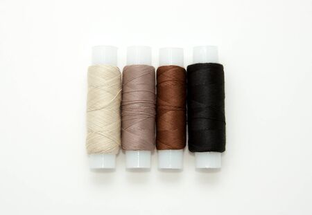 Flat lay colorful cotton thread spools, embroidery yarn, white, brown, black, bobbins, mock up, top view. Layout mockup, blank white background needlework, sewing poster, banner. Empty space for text.の写真素材