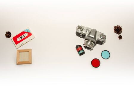 Old retro camera, color lens, cassette tape flat lay blank white background. Top view white poster mockup with space for text. Retro template poster, picture. White table, blank space, vintage camera.の写真素材
