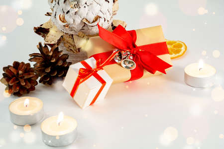Christmas table decoration close up banner. White hand made fir. Craft paper red gift boxes recycle nature materials candles lights pine cones white background. Minimalist new year copy space mock upの写真素材