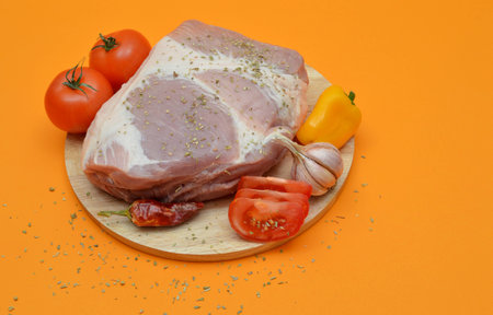Raw pork on a cutting board with vegetables.の写真素材