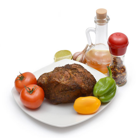 Roast pork on a platter with vegetables isolated on white.の写真素材