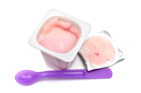 A Cup of yogurt with dessert spoon isolated on whiteの写真素材