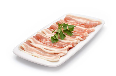 Slices of bacon with parsley on the plate isolated on whiteの写真素材