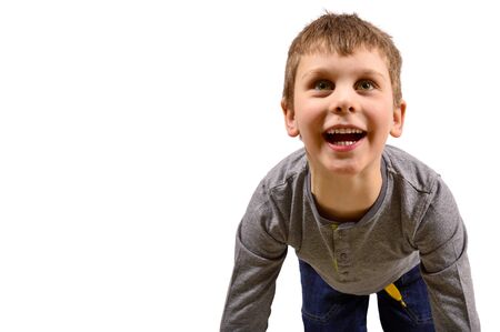 Happy laughing boy of five, having fun on his knees, looking up.の写真素材