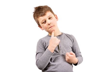 The boy squints, puts a finger to his chin, and thinks about something.の写真素材
