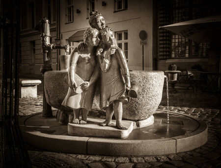A brass statue of three women gossiping whilst collecting water from the well in Stralsund, Germany, in sepia toneのeditorial素材