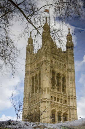 Victoria Tower attached to the Houses of Parliament, reflected in a puddle of water.のeditorial素材