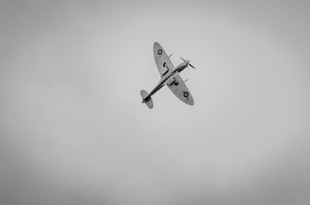 HEADCORN, KENT, ENGLAND - 15 AUGUST 2015: The undercarriage of a lone Spitfire aeroplane in flight in greyscaleのeditorial素材