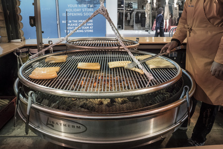 Large round barbecue with bratwurst sausages grilling on the griddle in the German Xmas market, Birmingham, UKのeditorial素材