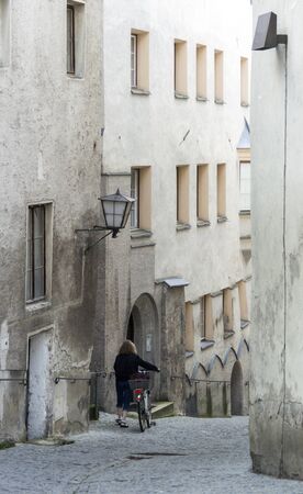 A lady pushing her bicycle in a narrow street in the ancient town of Hall in Tirol, Austria