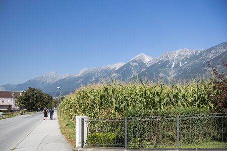 A man and woman walking along the road with the Austrian Alps in the background