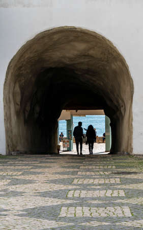 Silhouette of a couple walking through a pedestrian tunnel to the beach in Albufeira in the Algarve, Portugalのeditorial素材