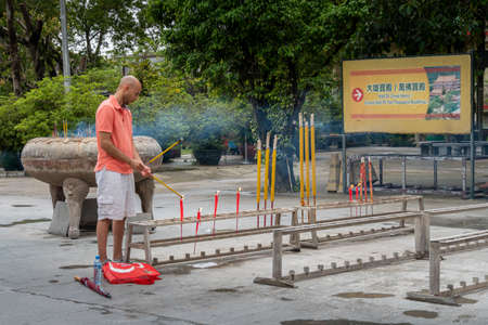 A man lighting incense sticks at Po Lin Monastery, Lantau Island, Hong Kongのeditorial素材