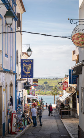 A narrow street with bars and souvernir shops in the town of Alvor, Algarve, Portugalのeditorial素材