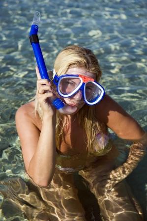 Young happy beautiful summer diving woman with swimming mask and snorkel preparing to dive in blue seaの写真素材
