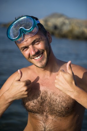 Young happy handsome summer diving man with swimming mask and snorkel preparing to dive in blue seaの写真素材