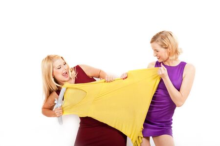 two beautiful shopping girls fighting for a dress. isolatedの写真素材