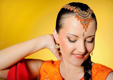Young beautiful woman in indian traditional jewellary, bindi and sari dress. yellow backgroundの写真素材