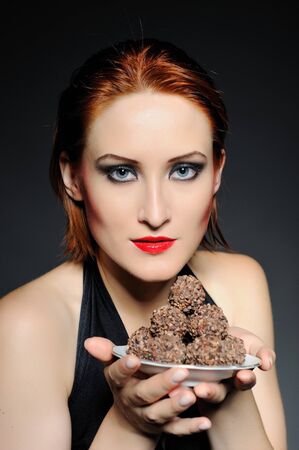 Beautiful retro woman with red lips holding many truffel shocolate sweets. の写真素材