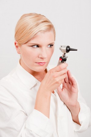 Beautiful female doctor in white medical uniform and tool for checking ear illnessesの写真素材