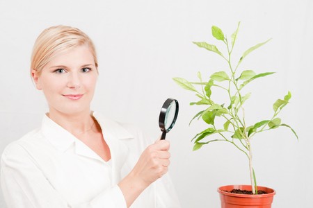 Beautiful female botanic scientist in white uniform and green plantの写真素材