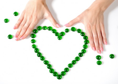 Beautiful hands building a heart sighn from green stones. isolated on white backgroundの写真素材