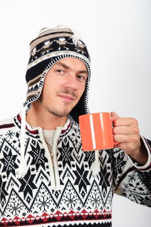 Handsome winter man in warm clothes and hat drinking hot teaの写真素材