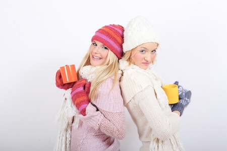 two beautiful winter woman friends in warm clothes drinking teaの写真素材
