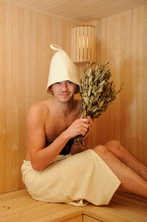 Young handsome man in a towel relaxing in a russian wooden saunaの写真素材
