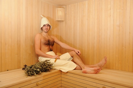 Young handsome man in a towel relaxing in a russian wooden saunaの写真素材