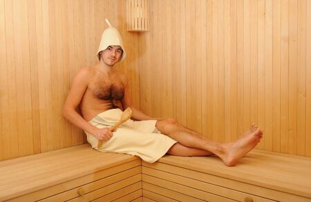 Young handsome man in a towel relaxing in a russian wooden saunaの写真素材