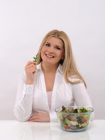 Pretty woman eating green vegetable salad. isolated on white の写真素材