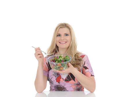Casual woman eating healthy green vegetable salad. isolated on white の写真素材