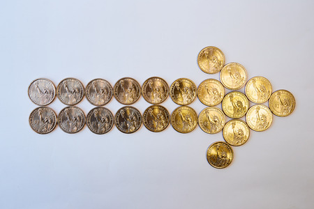 Design element. The gold yellow arrow to the right is lined with coins of one US dollar. In the center - half a dollar. Top view.の写真素材