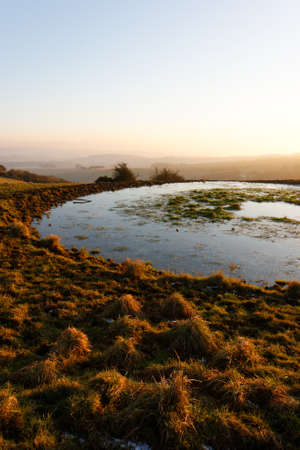 Water reservoir or Dew Pond on the South Downs near devils dyke during sunset in winter
