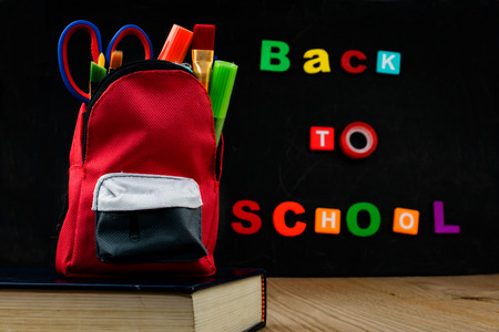 ACCESSORIES IN STUDENT BAG WITH BLACK CHALK BOARD. BACK TO SCHOOL TEXT.の写真素材