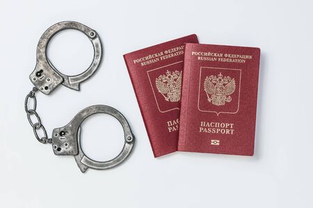 Two Russian passports with handcuffs on a white backgroundの写真素材